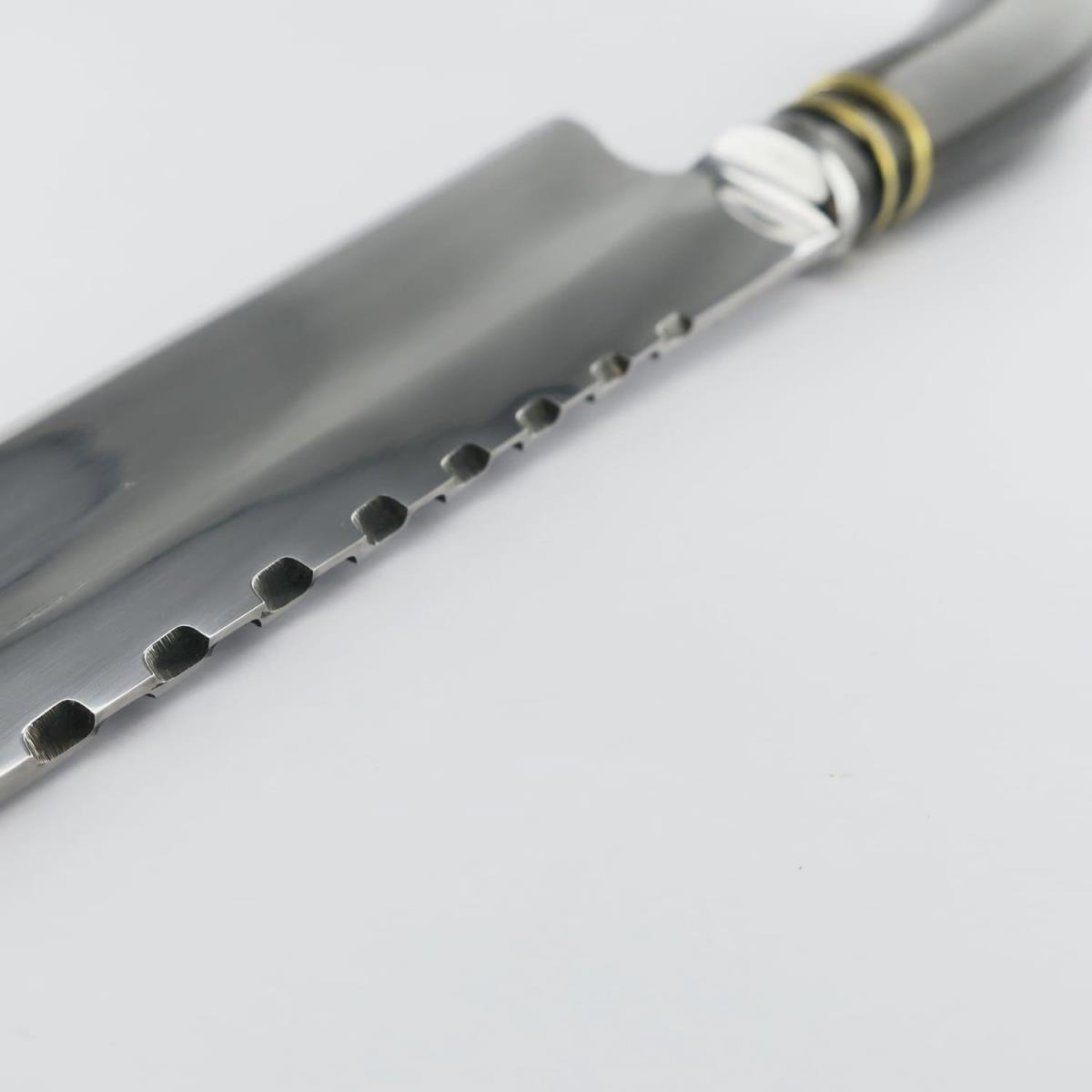 Close-up of a Cow 7.1in Dark stainless steel knife, featuring a sleek silver blade with unique indentations along the spine and a stylish handle with gold and silver accents, ideal for kitchen tasks.